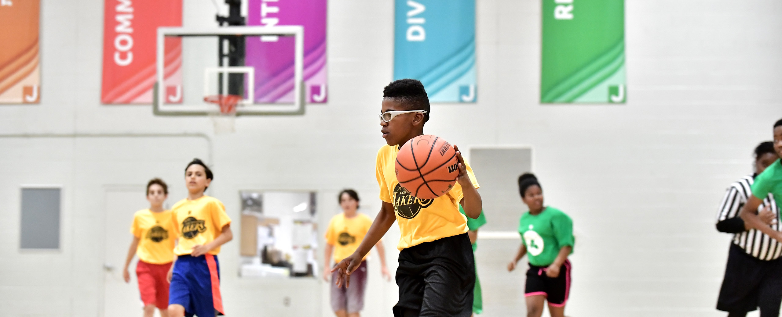 Kids playing basketball in a gymnasium.