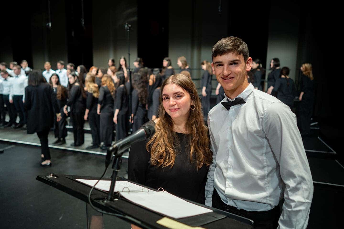 smiling teens in front of microphone and choir