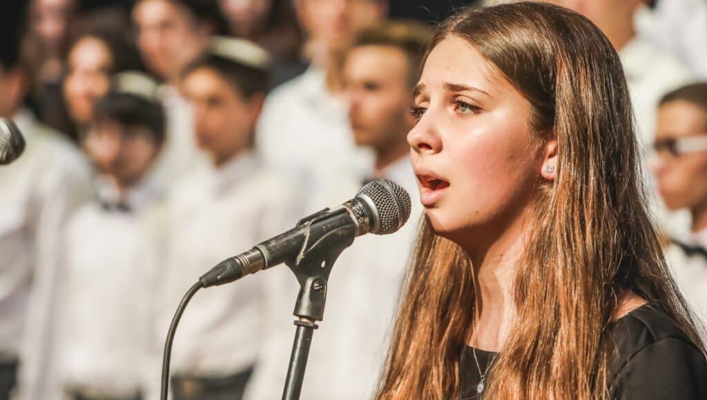 teen girl singing at microphone in front of choir