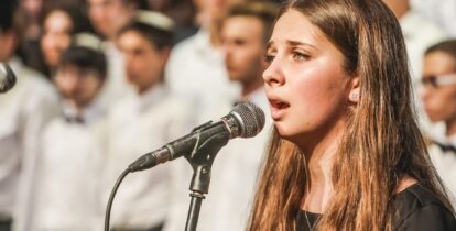 teen girl singing at microphone in front of choir