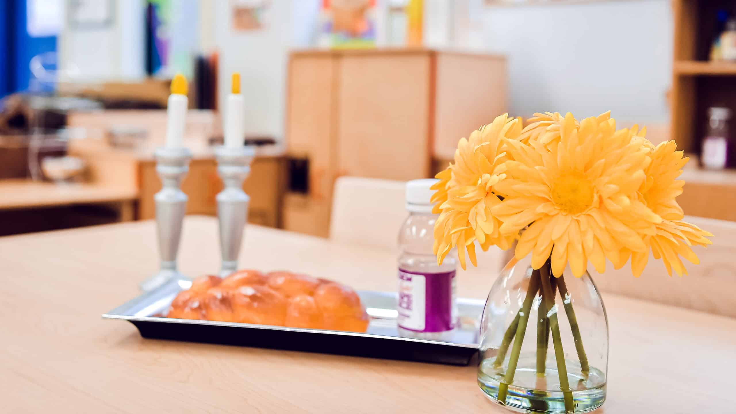shabbat candles and challah with flowers