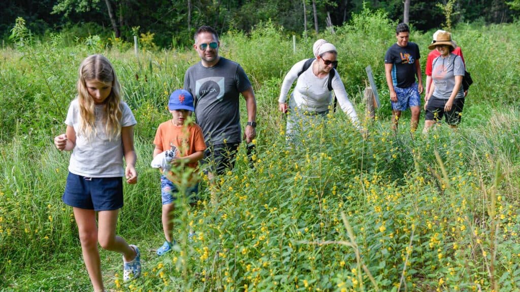 Family walking through field of grass and flowers