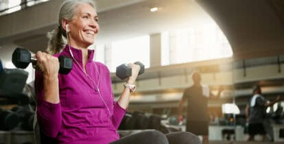 Senior woman lifiting light weights in gym