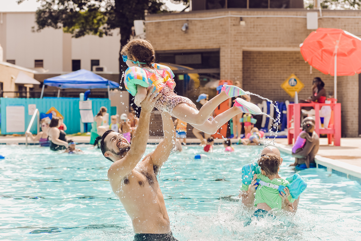 family playing in outdoor pool