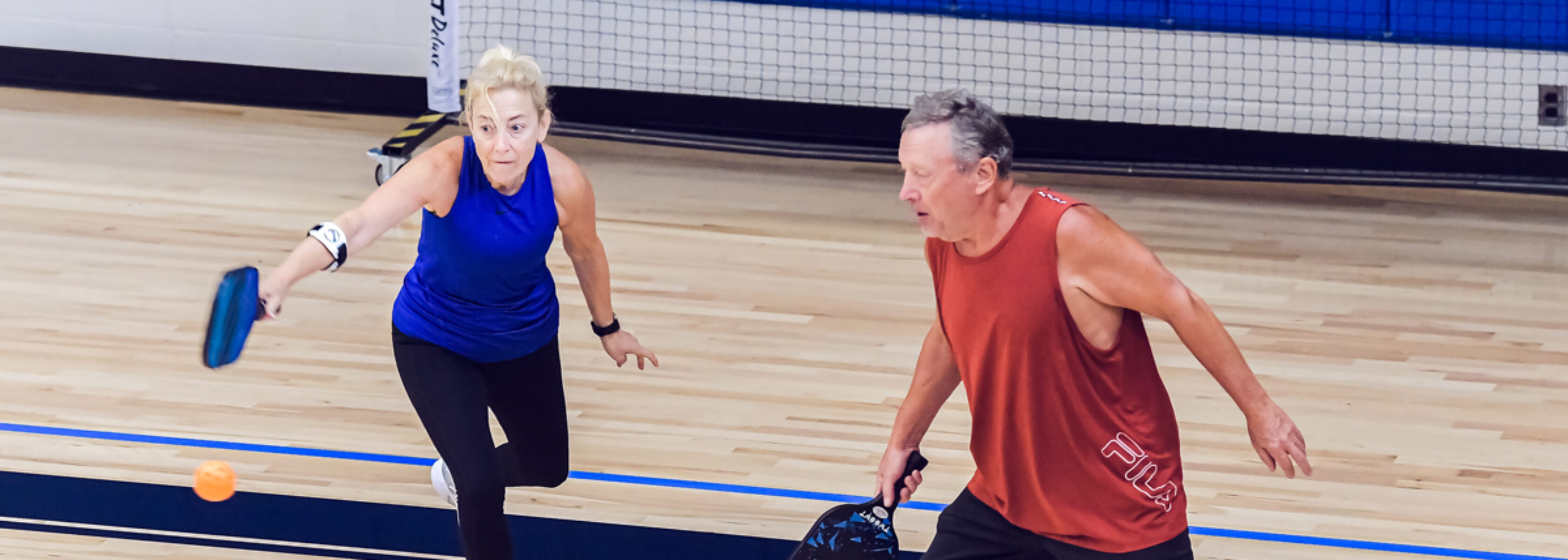 couple playing pickleball on indoor court